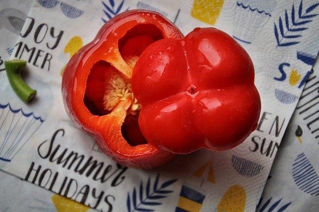 A red bell pepper cut in two uneven pieces on a napkin.