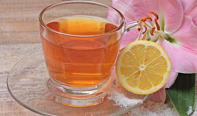 Cup of tea with a lemon on a small glass tray.