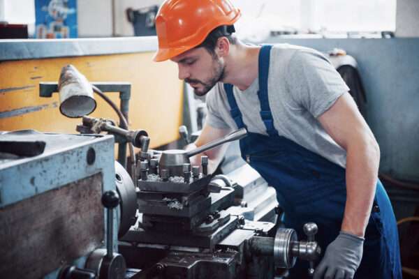 Portrait of a young worker in a hard hat at a large waste recycling factory. The engineer monitors the work of machines and other equipment